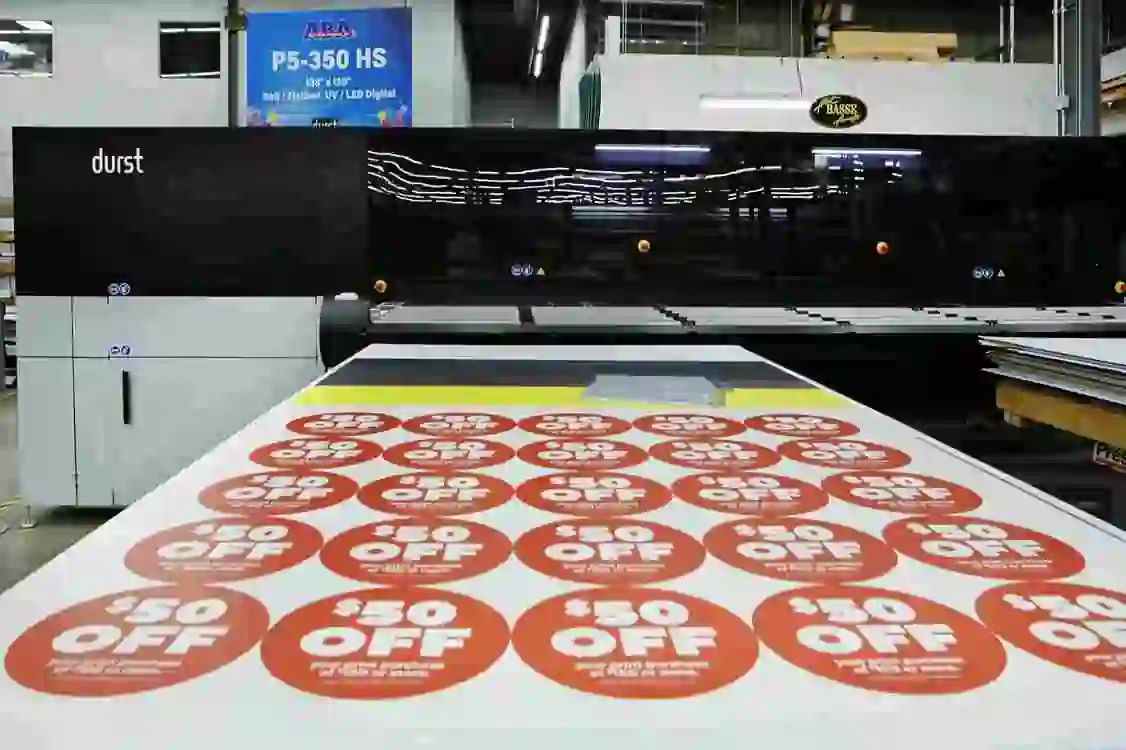 image shows a large format digital printer, specifically a Durst P5-350 HS, being used to print circular "50 OFF" discount stickers