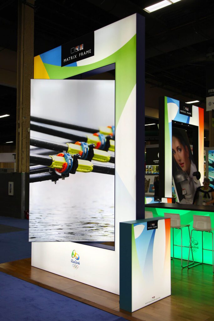image displays a trade show booth featuring a "Matrix Frame" light box display system, likely for an exhibition or event, given the "Rio 2016" Olympics branding visible on the lower panel.